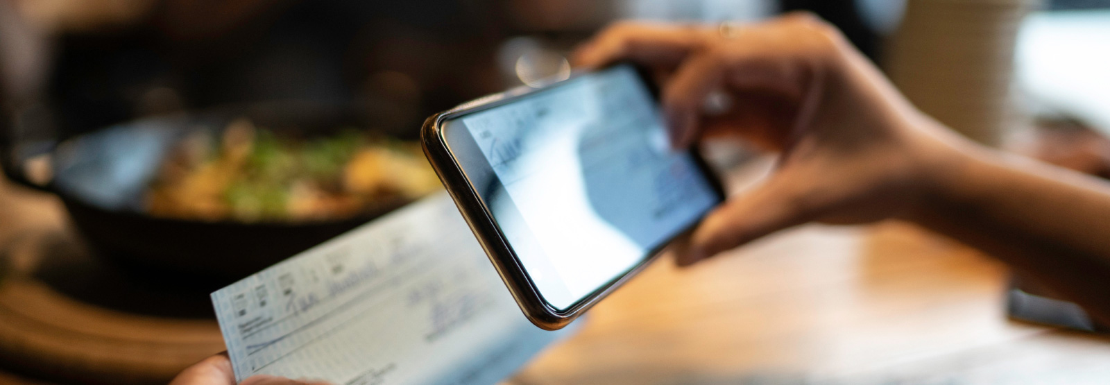 person using a smartphone to scan a paper bank check